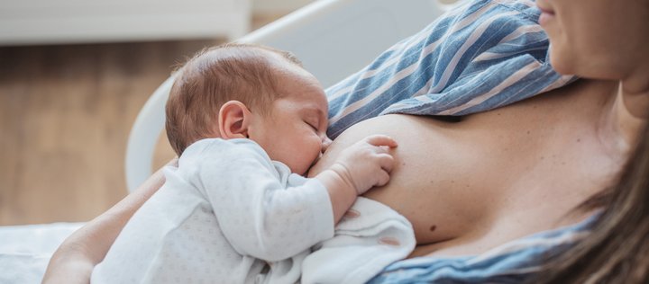 Frau stillt Baby in zurückgelehnter Stillhaltung