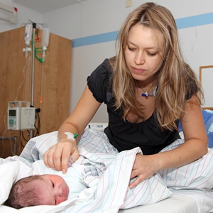 Müde Mutter auf Krankenhausbett mit Neugeborenem